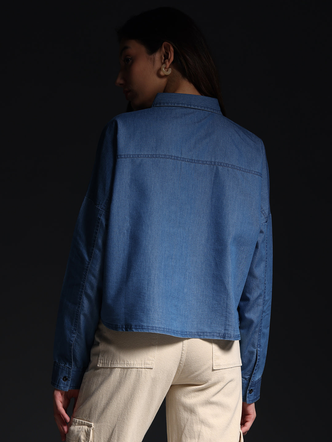 Back view of woman wearing Gotamoda autumn petals shirt in blue denim with beige pants