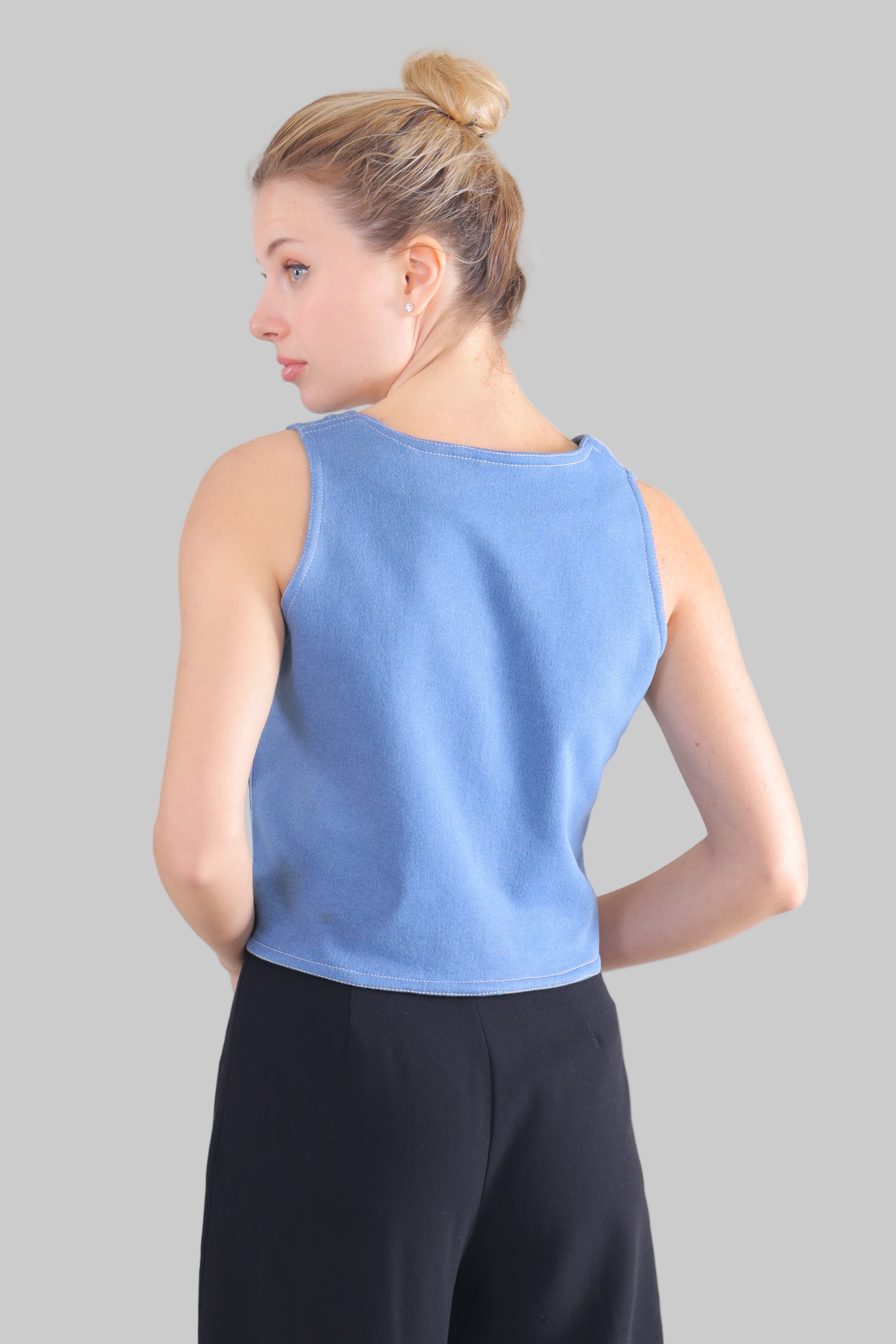 Back view of woman wearing light blue sleeveless jeans Top paired with black pants