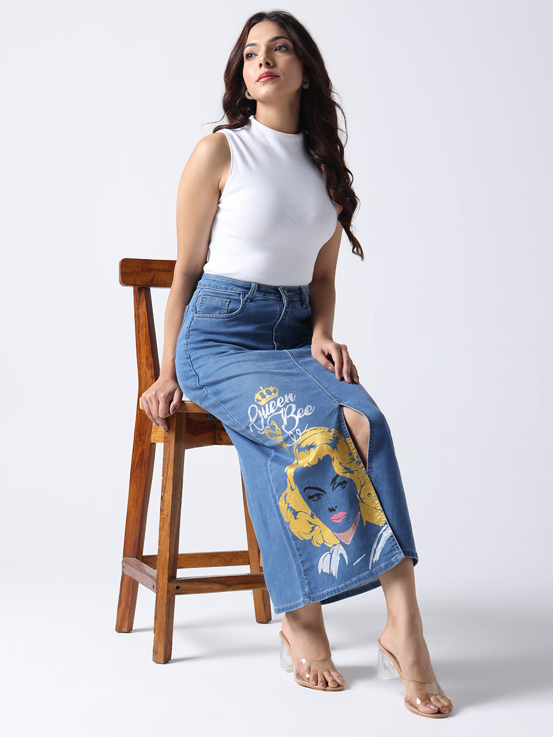 Gotamoda queen bee denim midi skirt with graphic print worn by woman sitting on wooden chair
