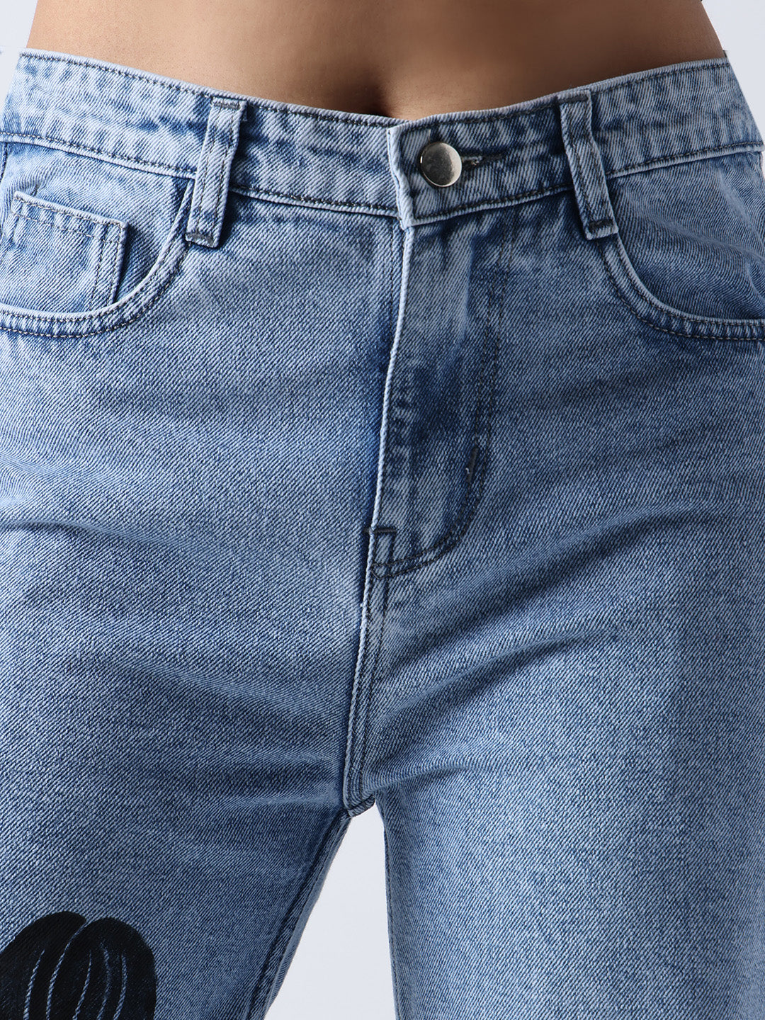 Close-up of Gotamoda hand painted jeans showing button closure and denim texture