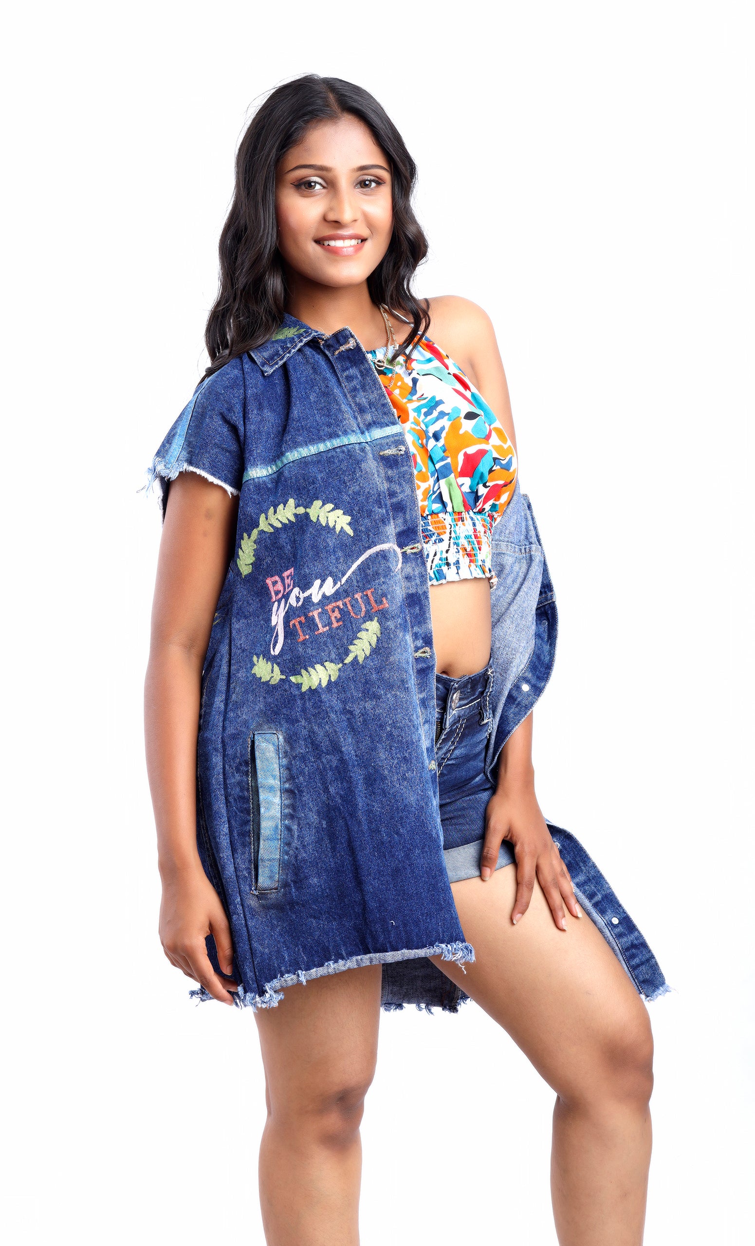 Gotamoda sleeveless denim jacket with frayed edges and embroidered design worn over colorful crop top and shorts