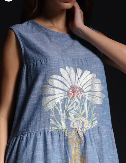 Close-up of a woman wearing hand-painted denim for women dress featuring floral and symbolic motifs