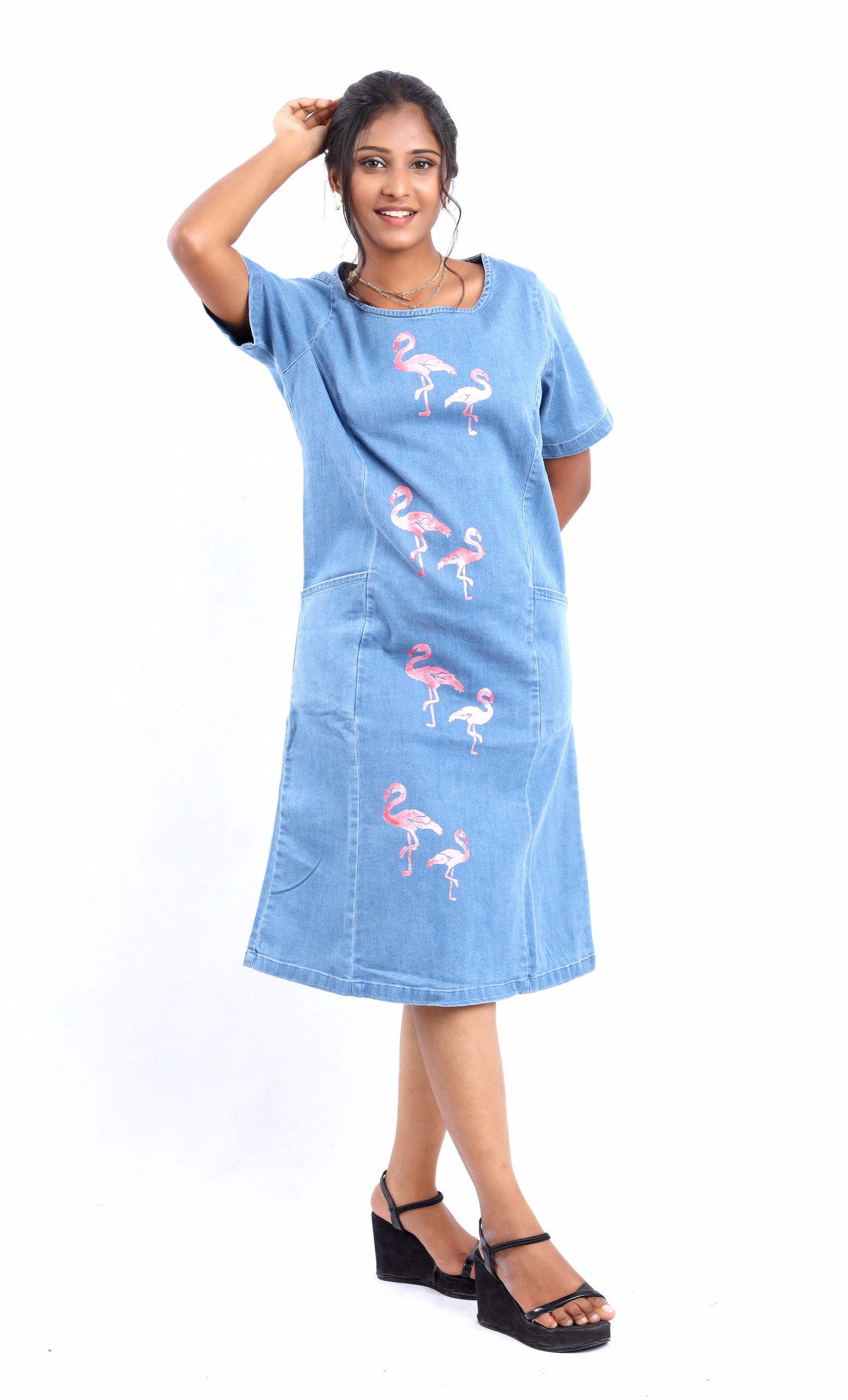 Woman wearing a denim midi dress with pink flamingo prints from women's unique midi dresses collection