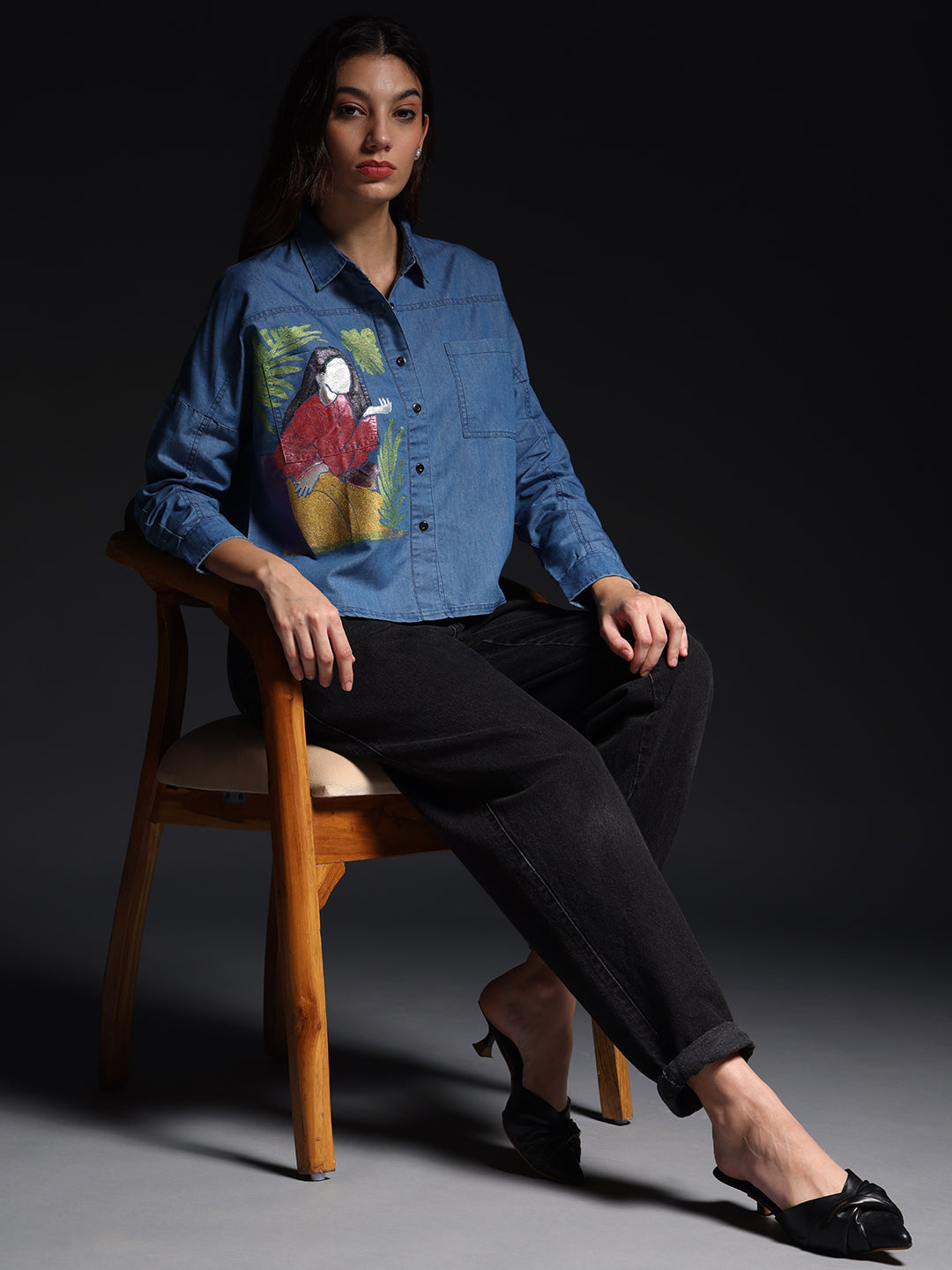 Woman wearing a stylish blue office wear shirts for women with artistic print sitting on wooden chair