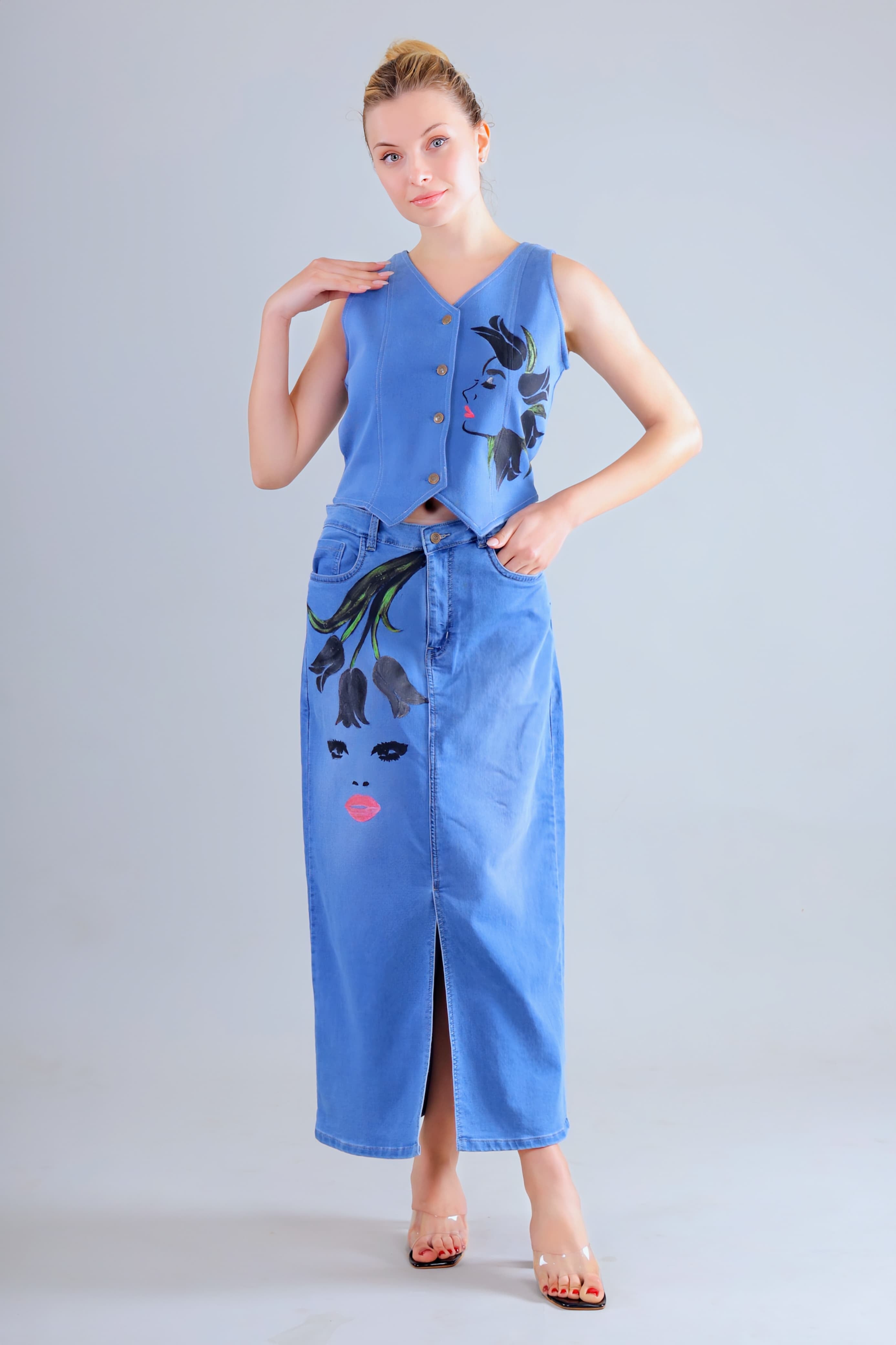 Woman wearing a hand painted denim co ord set women featuring floral and face designs with a sleeveless top and long skirt