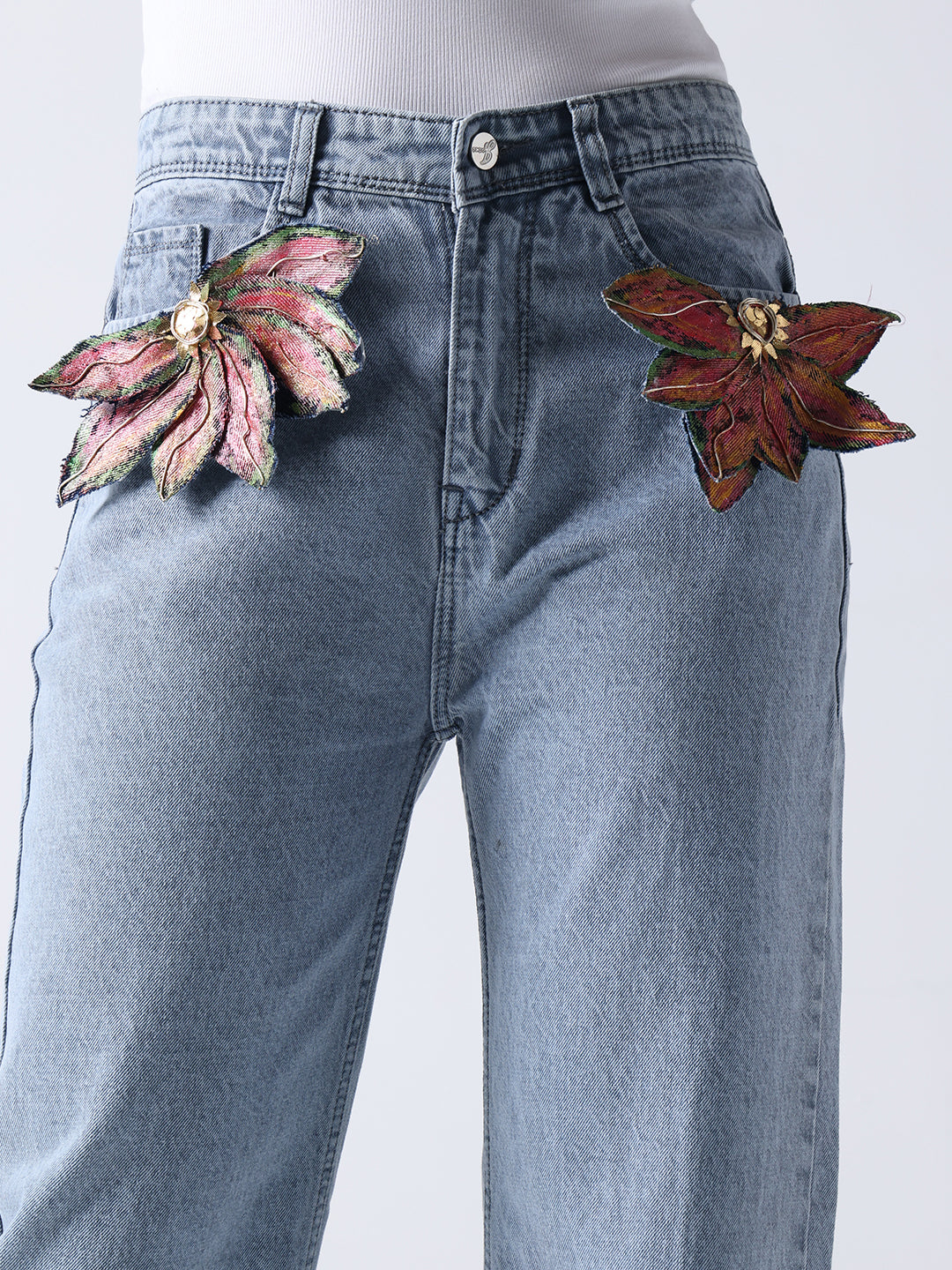Gotamoda brooch on jeans with two large floral designs pinned on light blue denim pants