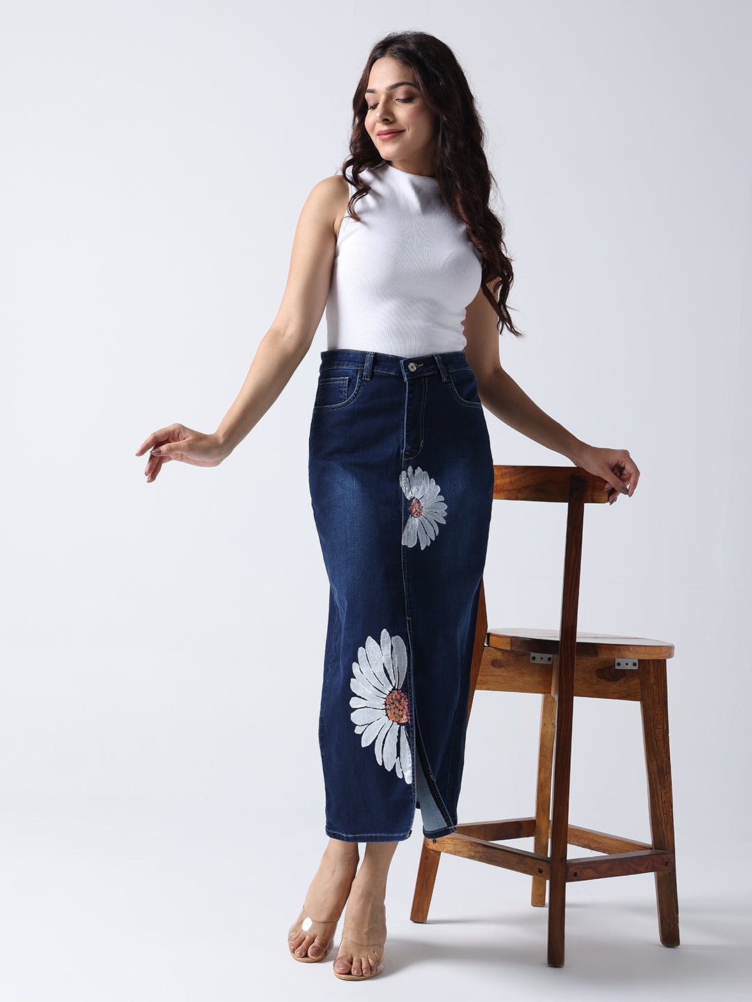 Woman wearing Daisy Dream Denim front cut Skirt with white daisy prints paired with sleeveless white top