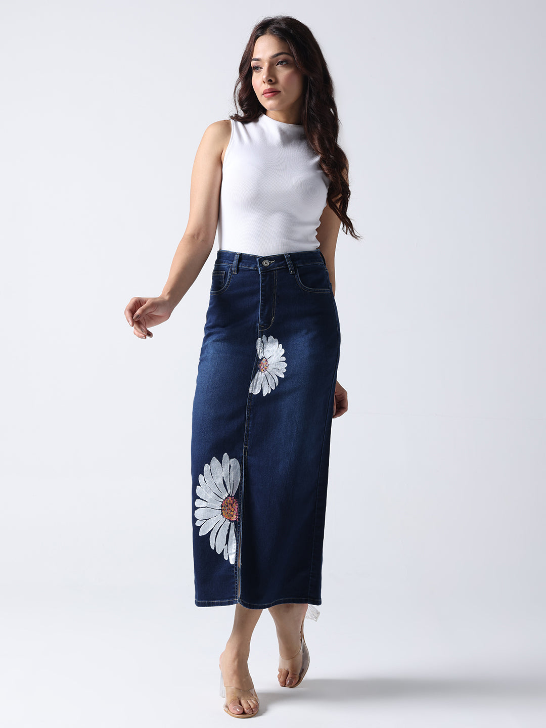 Woman wearing Daisy Dream Denim front cut Skirt with white daisy prints paired with a white sleeveless top