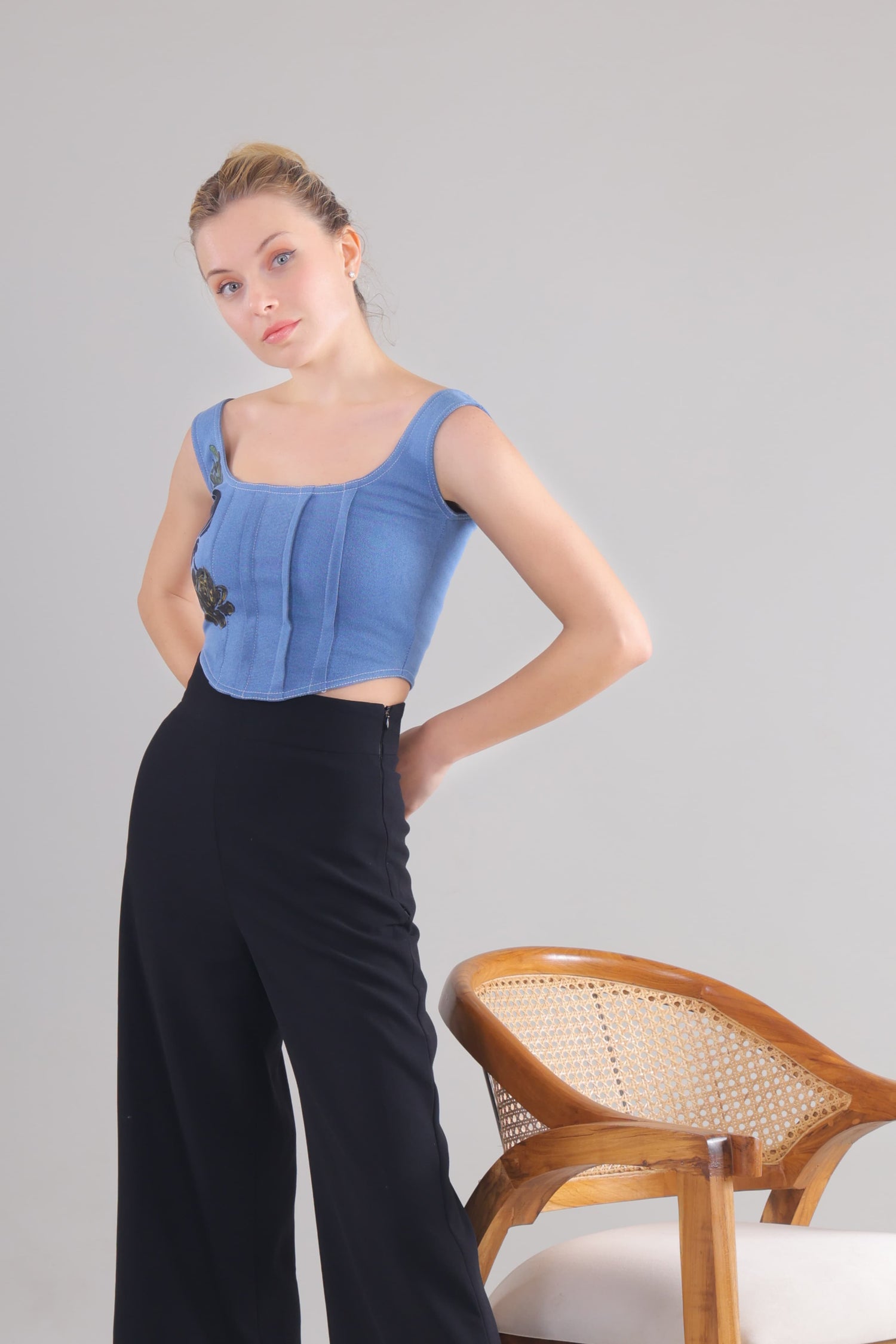 Gotamoda Denim Corset Top worn by model paired with black high-waisted pants and wooden chair nearby