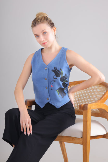 Gotamoda blue sleeveless jeans Top with button front and floral face design worn by seated woman