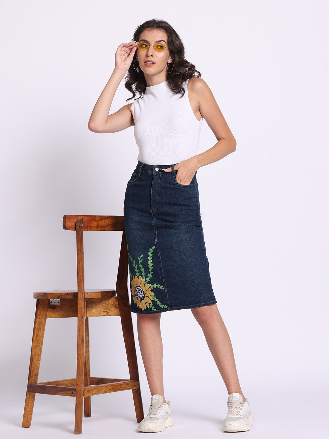 Gotamoda denim skirt with floral embroidery worn by model with white sleeveless top and white sneakers