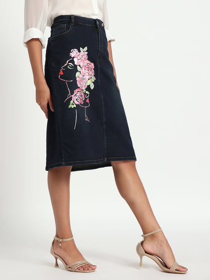 Gotamoda dark blue denim skirt with floral embroidery on side, worn with white blouse and beige heels