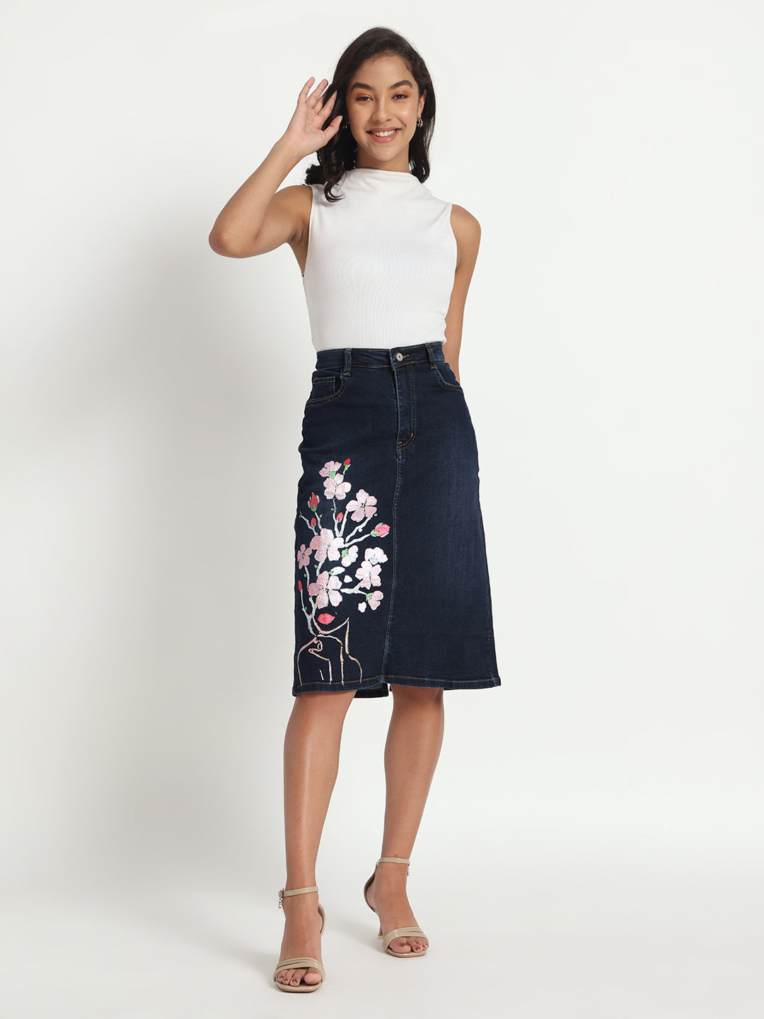 Dark blue jeans skirt for women with floral embroidery worn by model in white sleeveless top