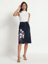 Dark blue jeans skirt for women with floral embroidery worn by model in white sleeveless top
