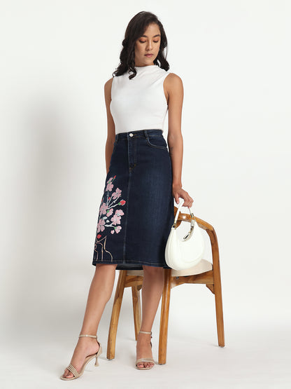 Gotamoda dark blue jeans skirt for women with floral embroidery styled with white sleeveless top and heels