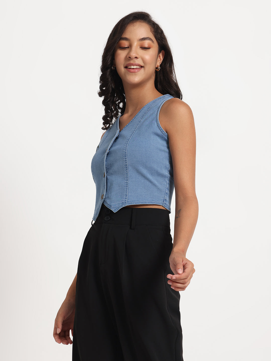 Gotamoda sleeveless blue jeans top with button front worn by woman paired with black pants