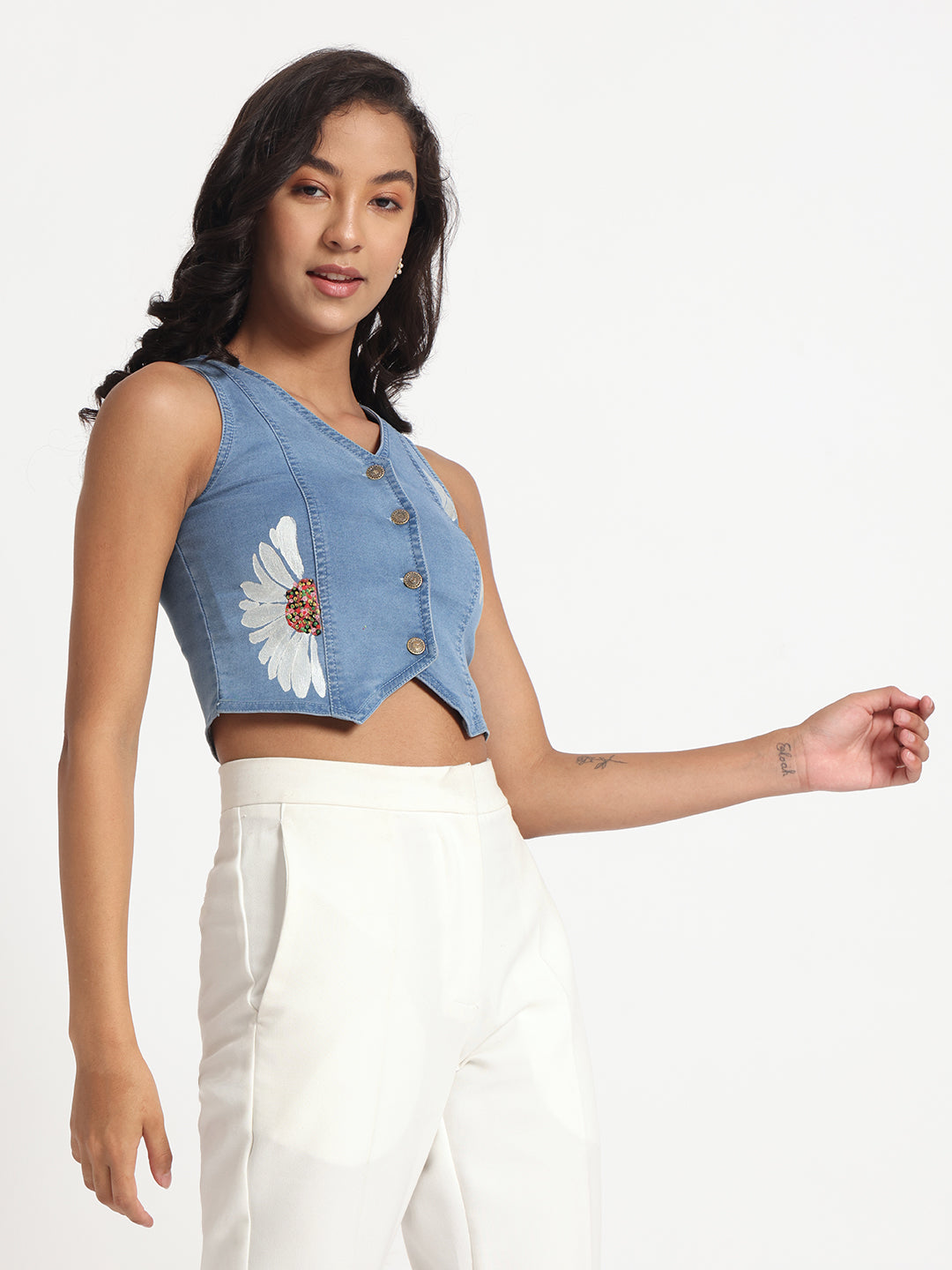 Gotamoda sleeveless top in jeans with front buttons and floral design worn with white pants