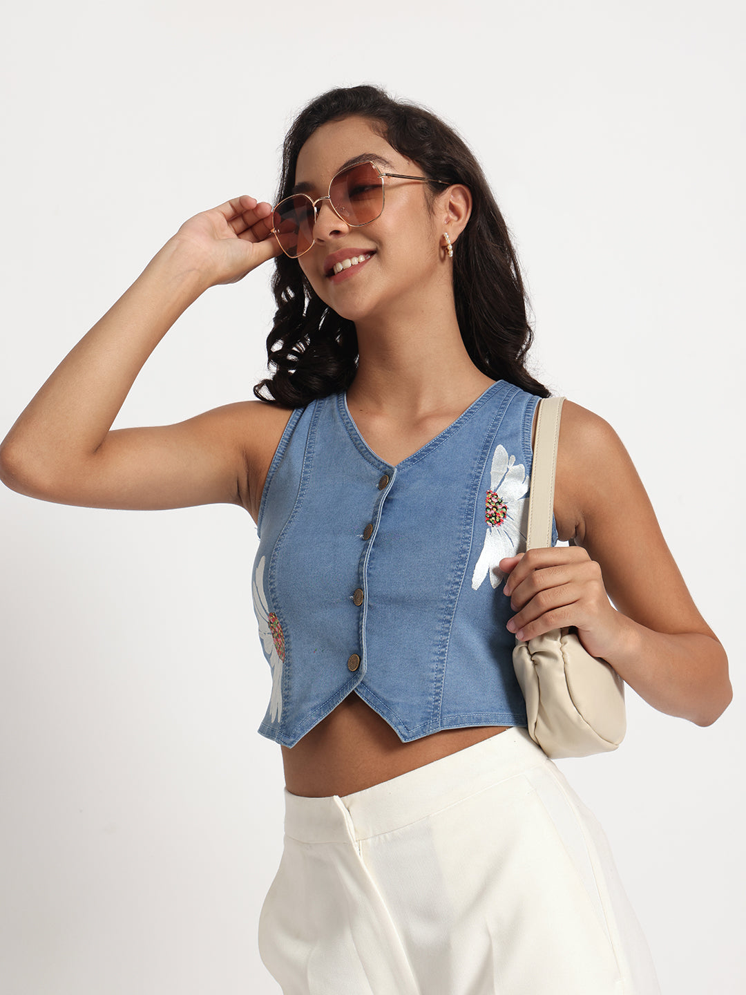 Gotamoda sleeveless top in jeans with floral embroidery worn by woman with sunglasses and white pants