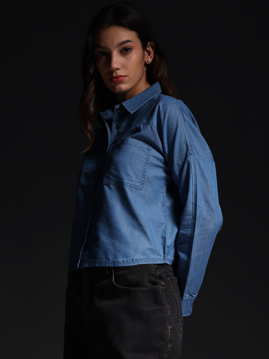 Gotamoda top jeans shirt in blue worn by woman paired with black jeans against black background