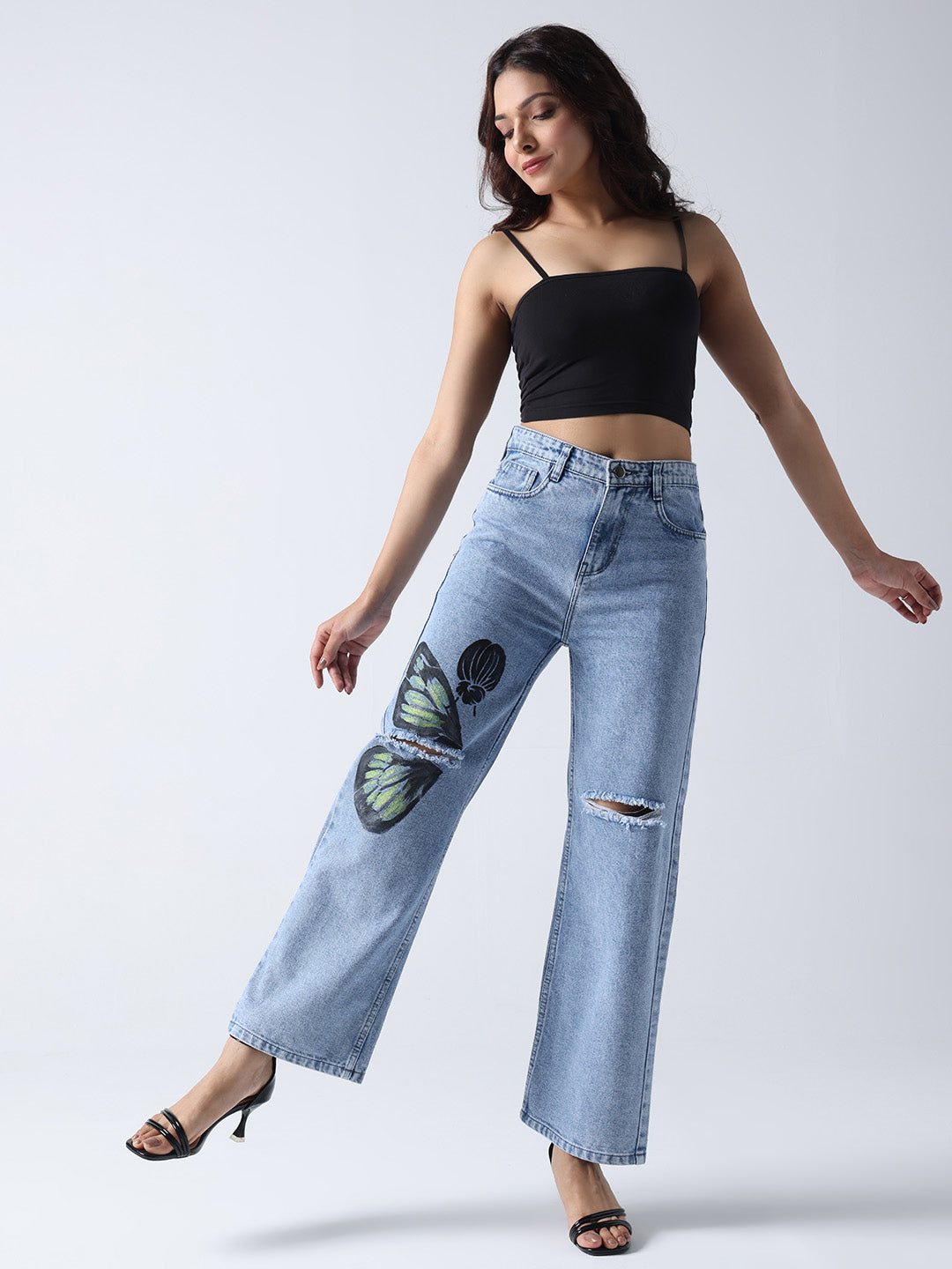 Gotamoda woman wearing light blue hand painted jeans with butterfly design and ripped knee