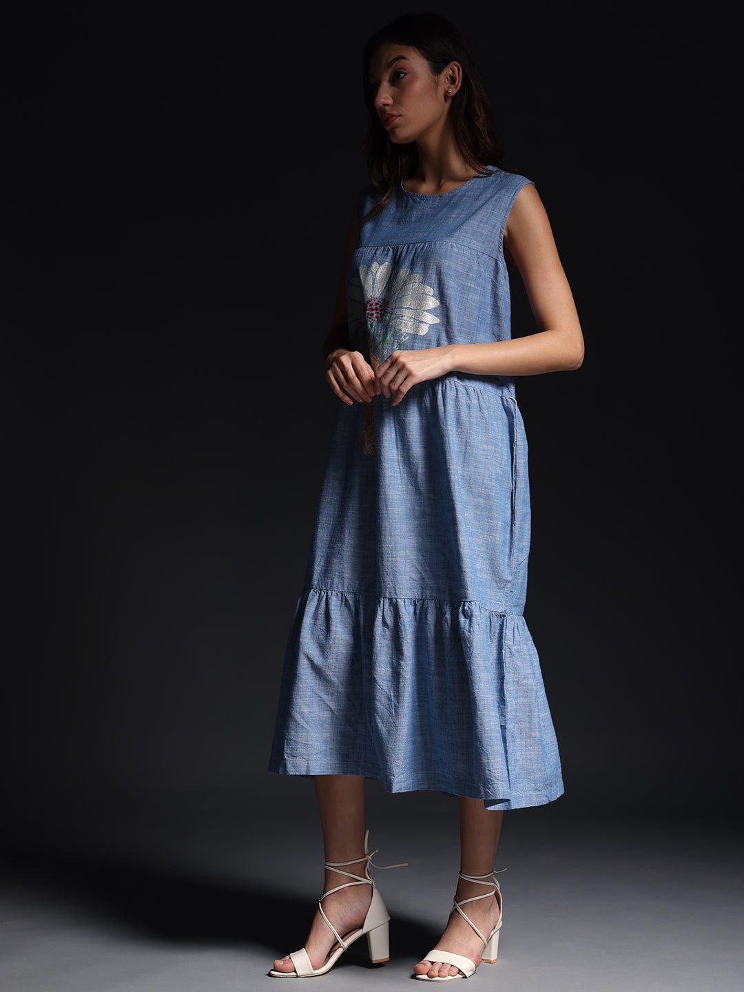 Gotamoda sleeveless maxi dress in blue with floral design and ruffled hem worn with white strappy heels